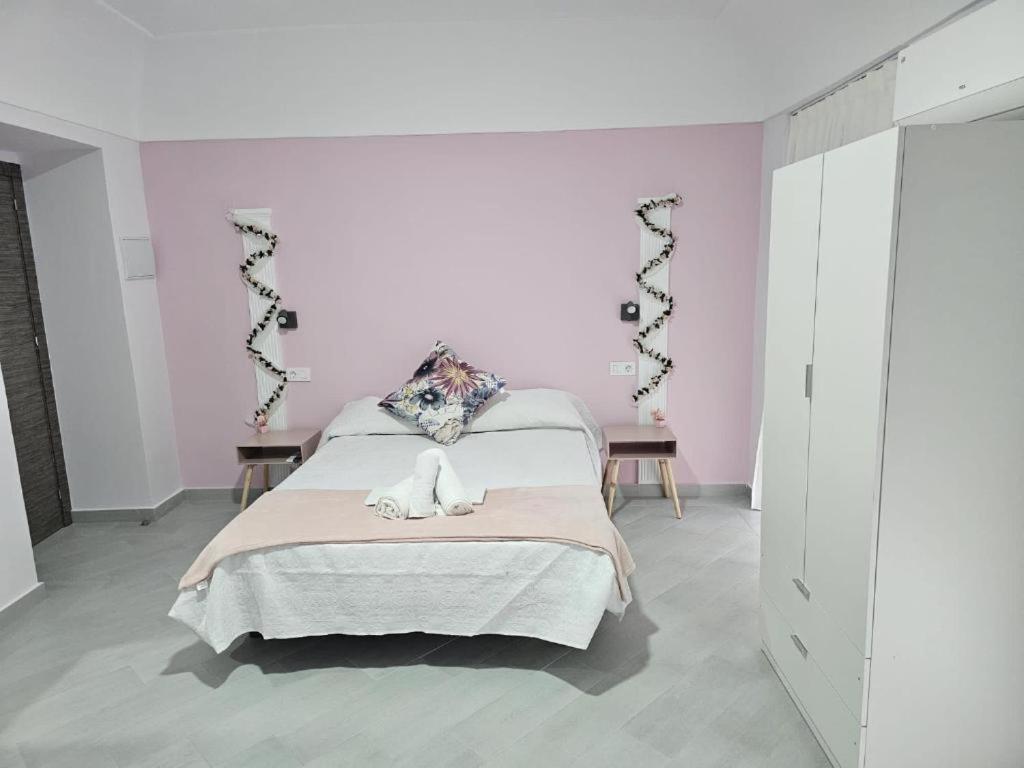 - une chambre avec un lit et un mur rose dans l'établissement Pompeya Merida suite, à Mérida