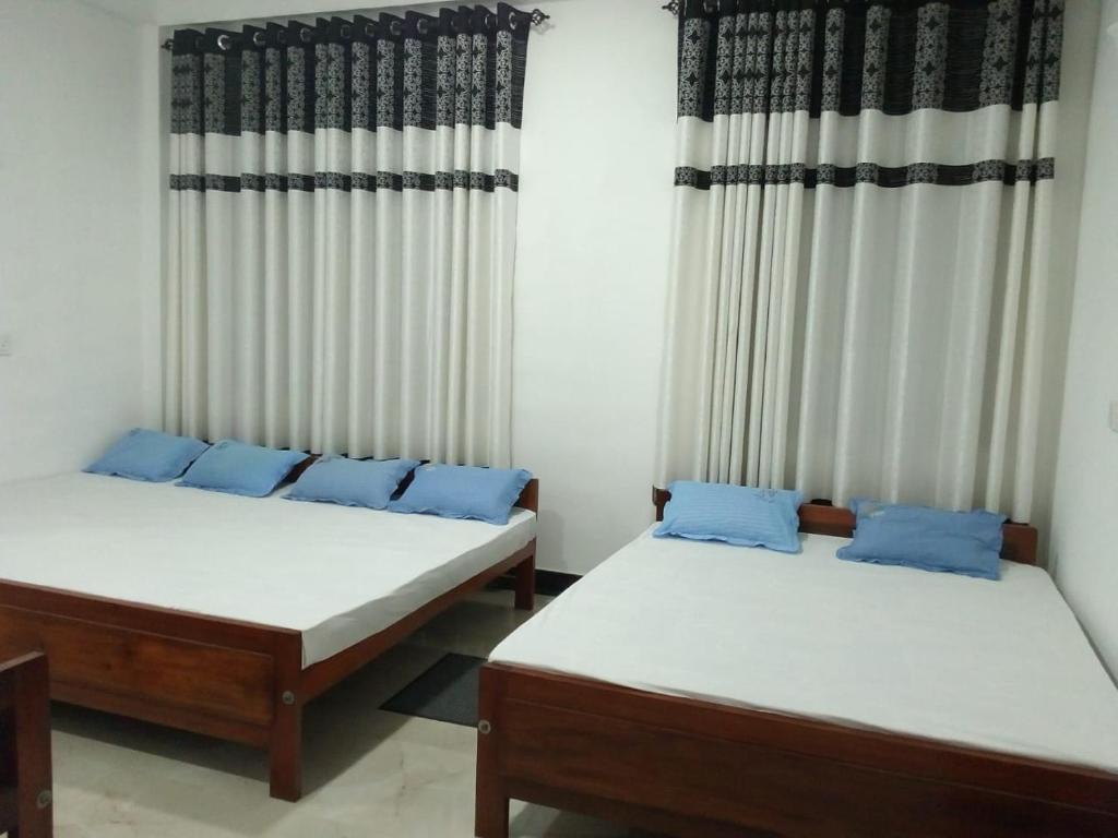 two beds sitting in a room with curtains at Sahasna Holiday Home in Diyatalawa