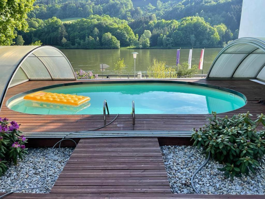 a swimming pool on a deck with a view of a lake at Bungalow Donaublick mit Pool und Garten in Sankt Nikola an der Donau