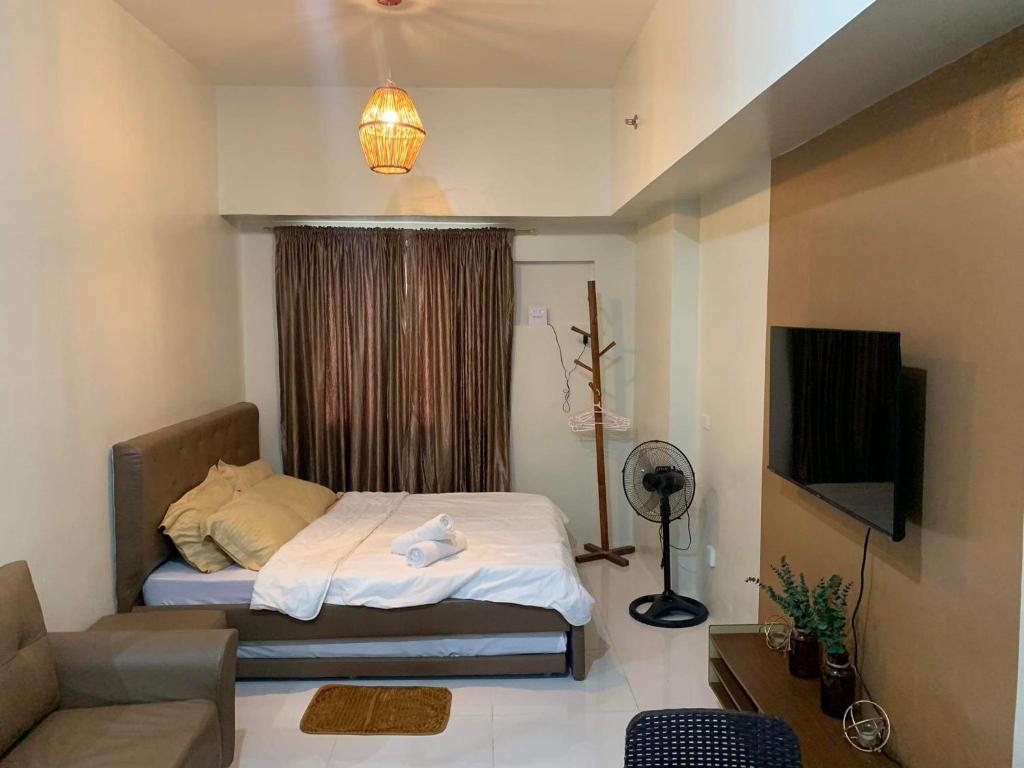 a bedroom with a bed and a couch and a television at Brenthill Condo (Ceramic Unit) in Baguio