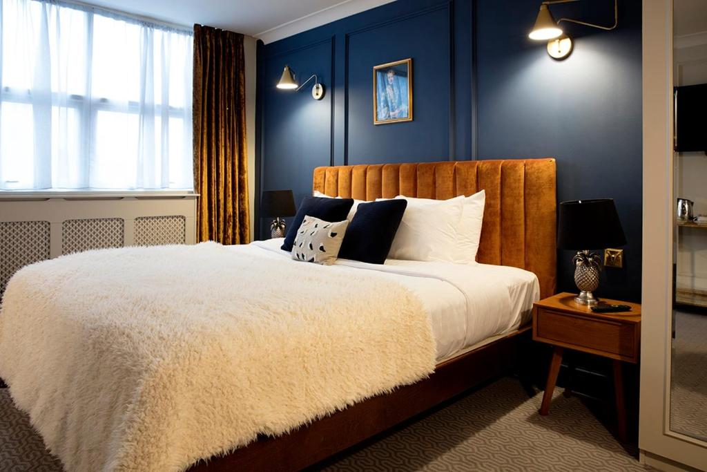 a bedroom with a large bed with blue walls at Hotel Cromwell Stevenage in Stevenage