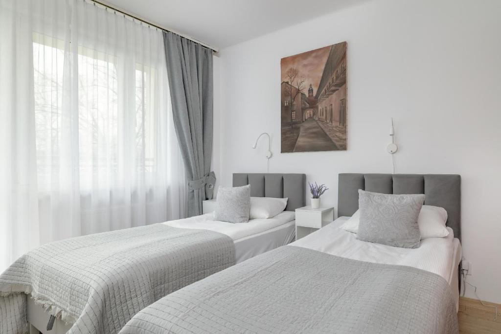 Cette chambre blanche dispose de 2 lits et d'une fenêtre. dans l'établissement Comfortable Apartment with Balcony in Krakow by Rent like home, à Cracovie
