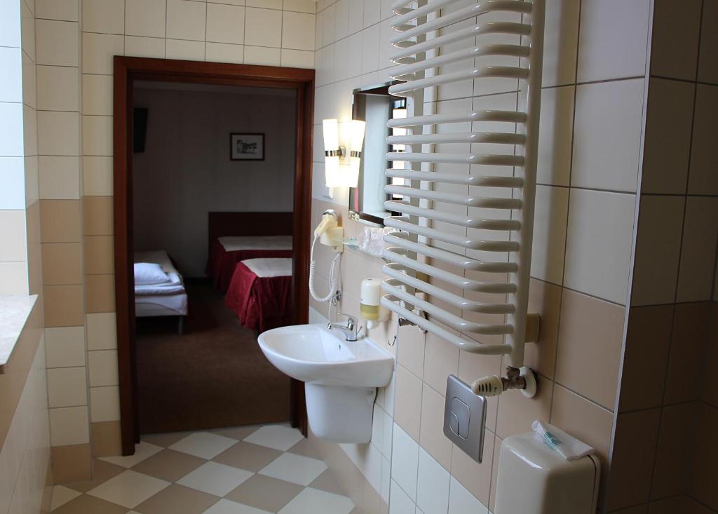 Bathroom corridor view showing sink and curved towel radiator, doorway to twin-bedded room beyond