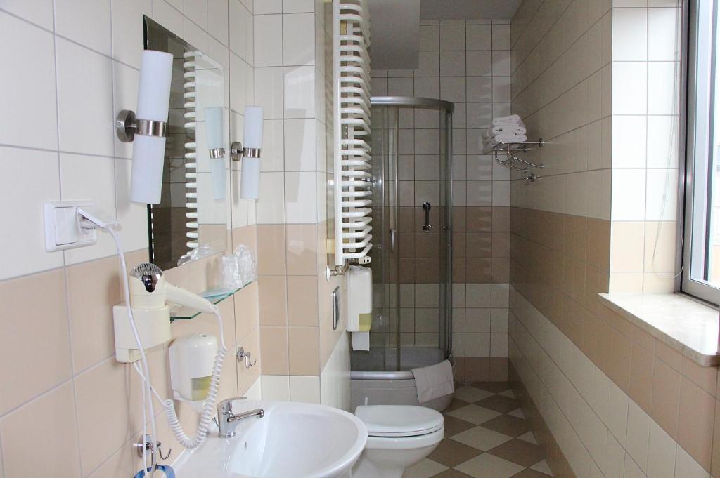 Long narrow bathroom with corner shower, toilet and sink beneath window, practical layout
