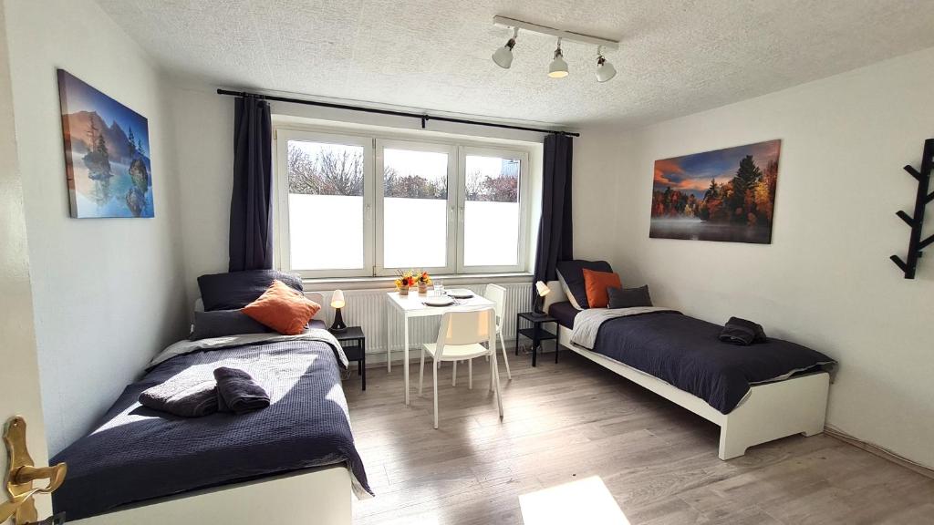 a bedroom with two beds and a table and a window at Helles Apartment für 5 Personen in Schwerte