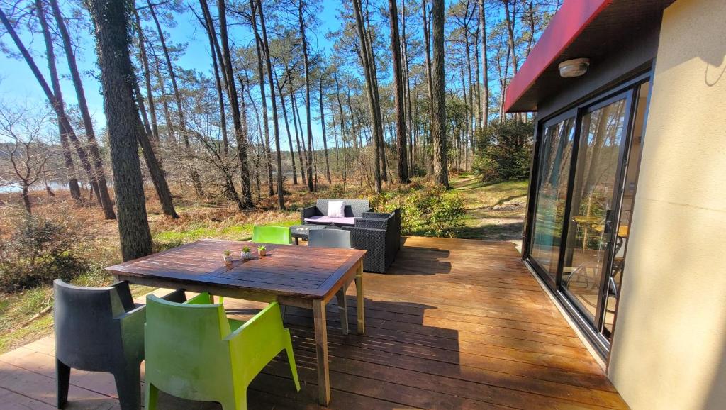 eine Holzterrasse mit einem Tisch und Stühlen auf einem Haus in der Unterkunft LE COTTAGE VUE LAC-2 vélos-Village Vacances Nature de 70ha! avec piscines et animations in Léon