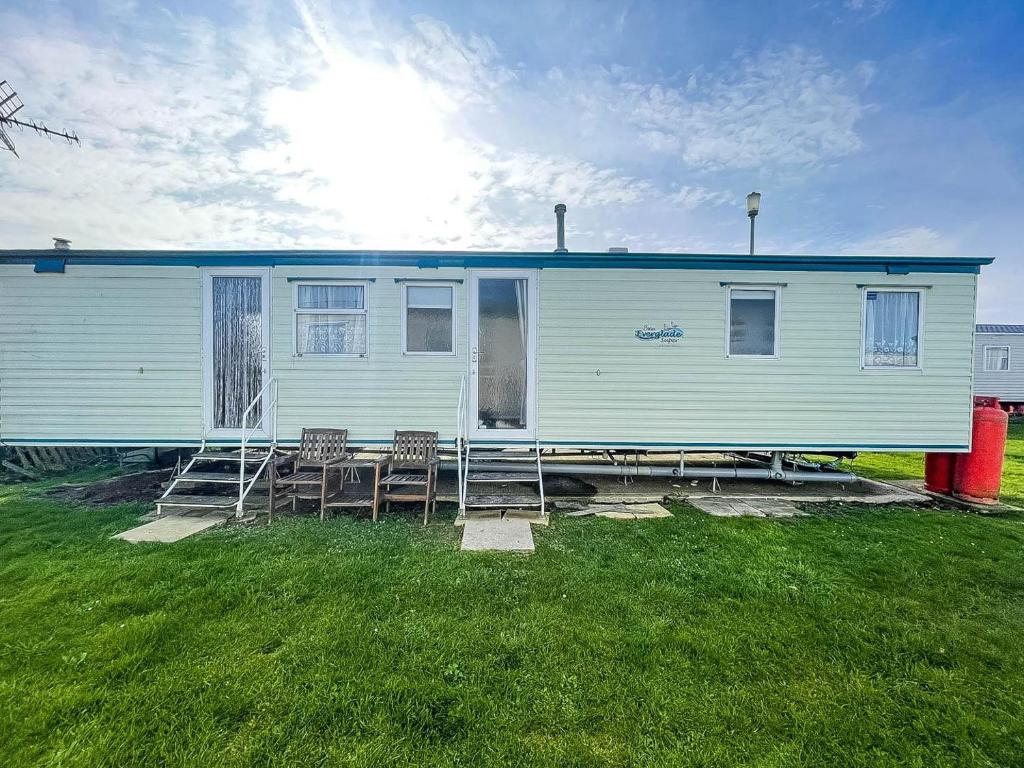 a white house with chairs and a table at 8 Berth Caravan With Wifi At Dovercourt Holiday Park In Essex Ref 44009e in Great Oakley