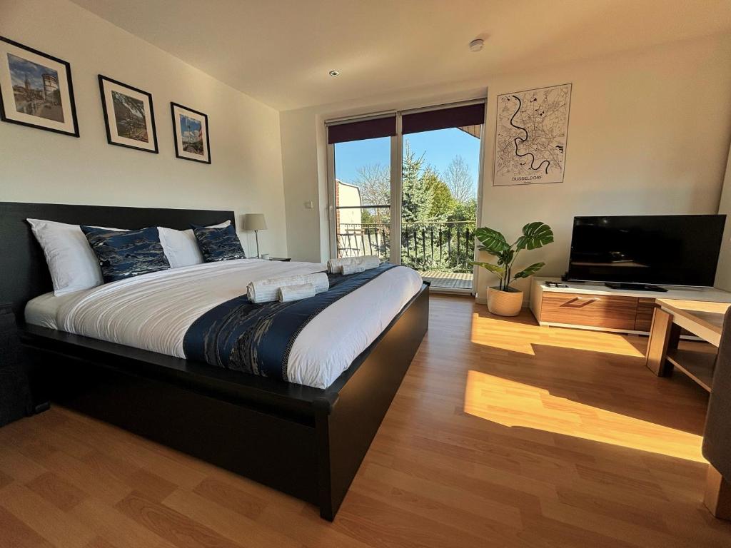 a bedroom with a large bed and a flat screen tv at Quiet Garden-View Studio Apartment in Düsseldorf