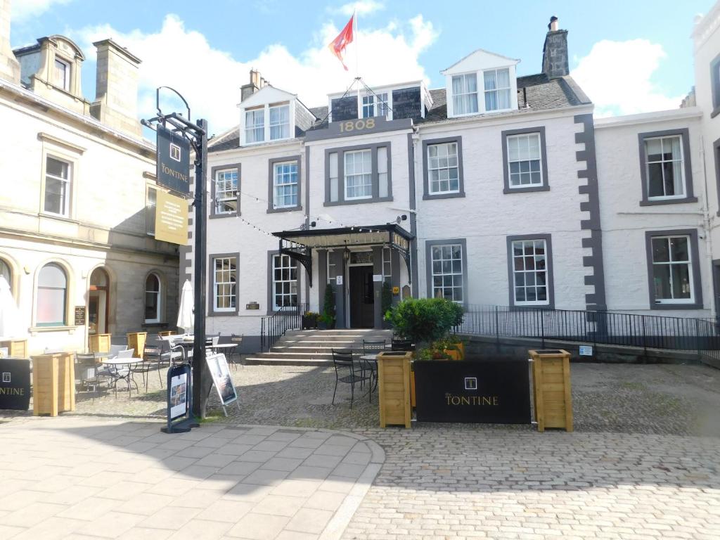 een groot wit gebouw met een bord ervoor bij The Tontine Hotel in Peebles