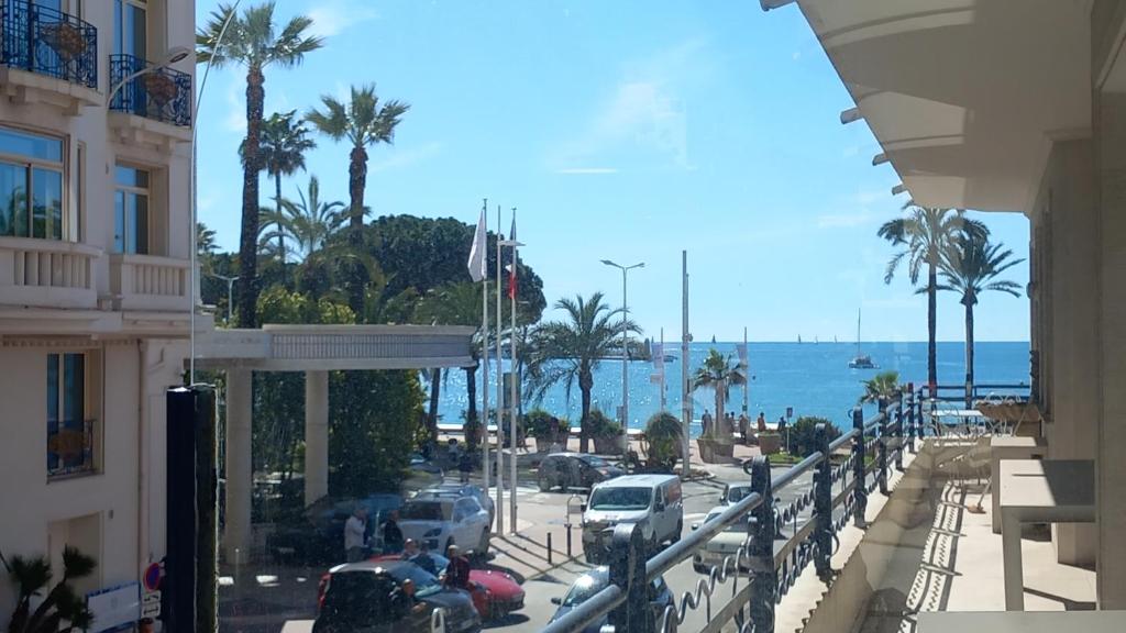 - une vue sur un parking avec des palmiers et l'océan dans l'établissement Le Palais Des Iles, à Cannes
