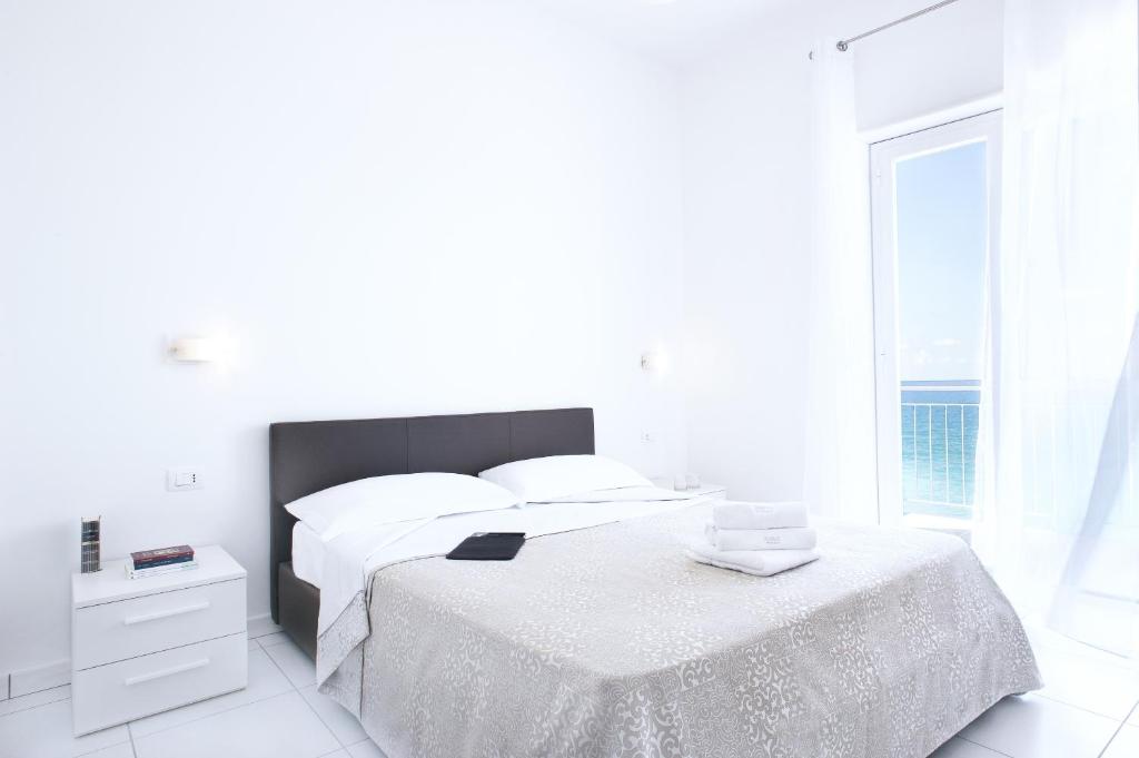 Un dormitorio blanco con una cama y una ventana. en Vuelle Residence Apartments, en Capo dʼOrlando