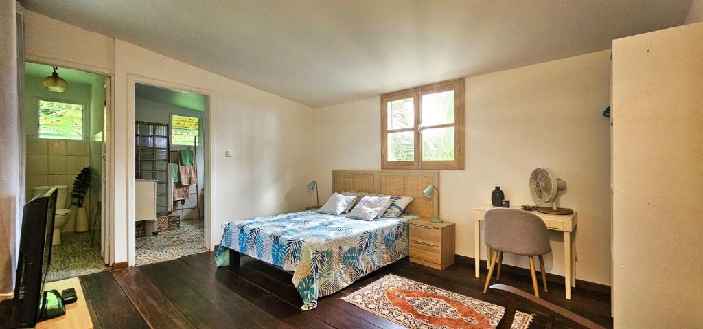 1 dormitorio con cama, escritorio y ventana en La Maison de Rosalie, meublé de tourisme classé, en Sainte-Rose