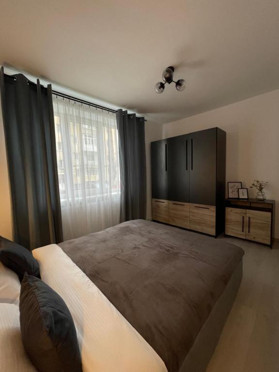 een slaapkamer met een groot bed en een groot raam bij Cozy Apartment Sfanta Vineri Zalau in Zalău