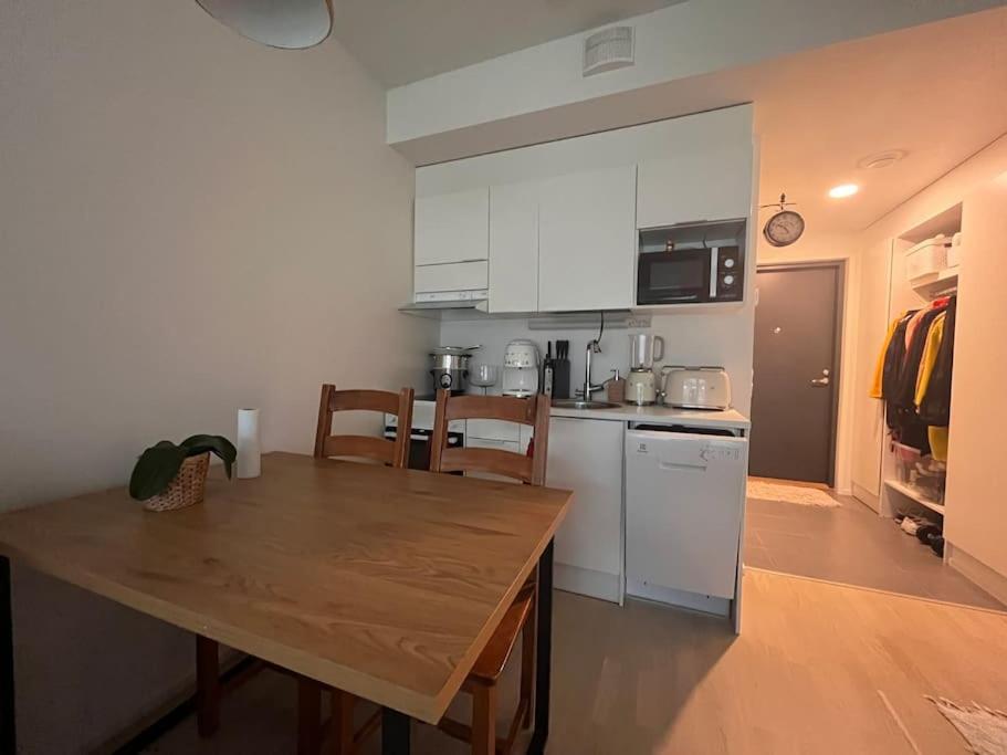 a kitchen with a wooden table and white cabinets at Ingas, Espoo- Whole apartment in Espoo