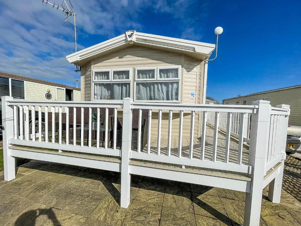 una cerca blanca frente a una casa en Lovely Caravan With Decking Wifi At Dovercourt Park, Essex Ref 44003bv, en Great Oakley