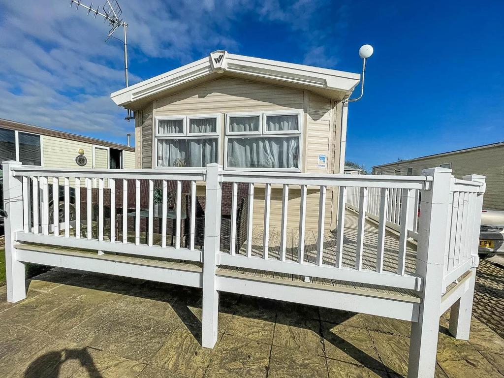 a white fence in front of a house at Lovely Caravan With Decking Wifi At Dovercourt Park, Essex Ref 44003bv in Great Oakley