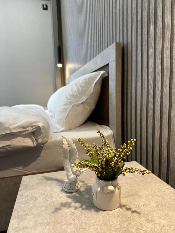 una mesa con un jarrón con flores junto a una cama en TURAN HOTEL, en Aktau
