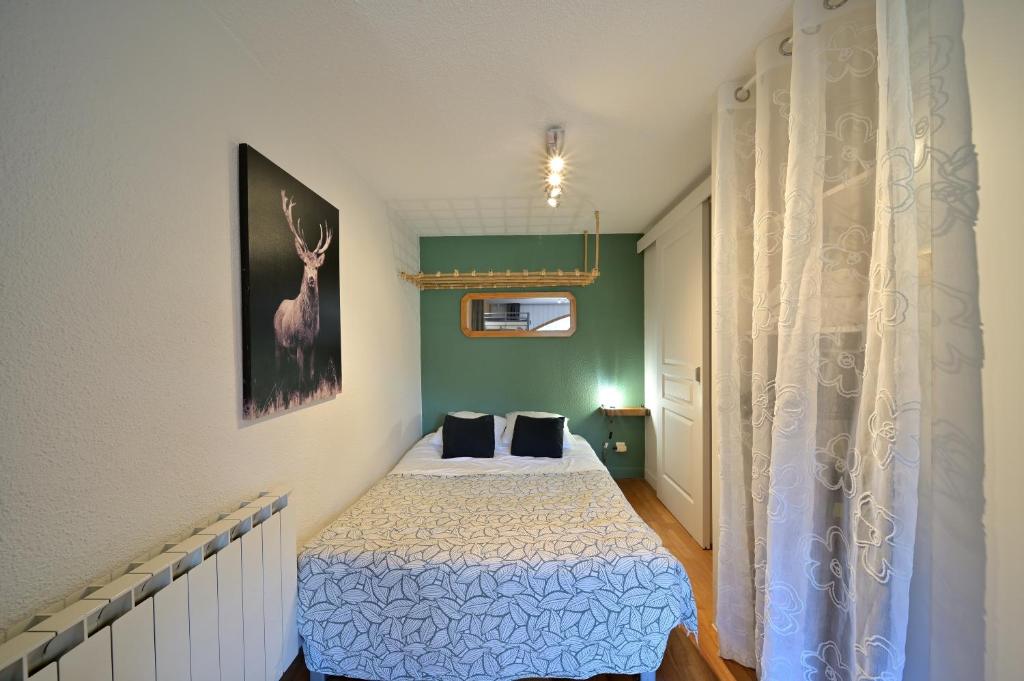 a bedroom with a bed with a deer picture on the wall at Studio 5 Pers Face Au Lac Payolle in Campan