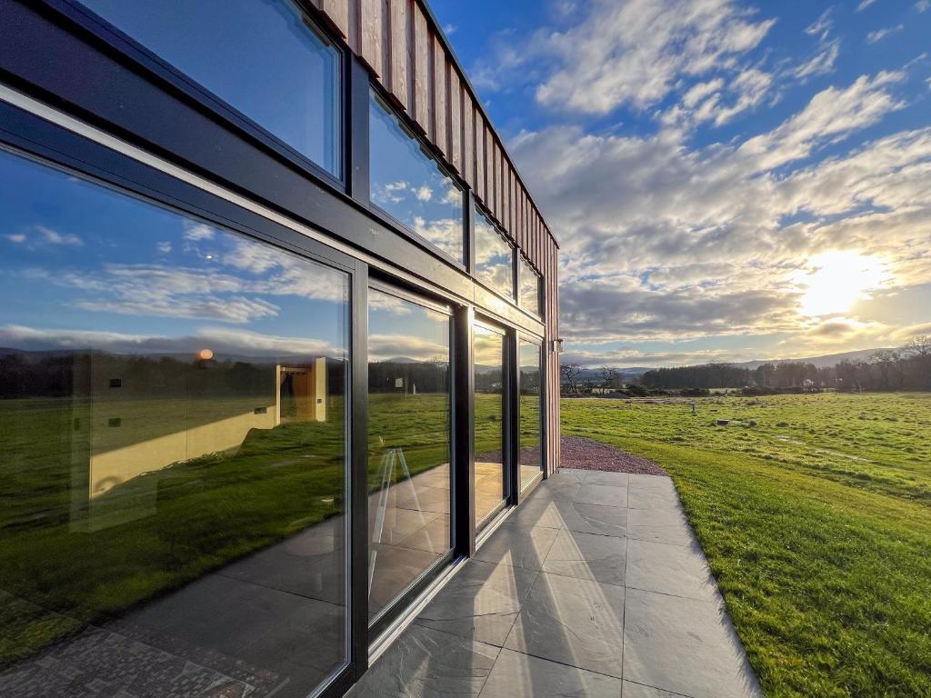 a glass building with a view of a field at Tillyfruskie Farm Cabin in Banchory