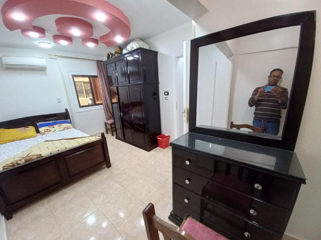 a man taking a picture in a mirror in a bedroom at Light moon appartment in Luxor