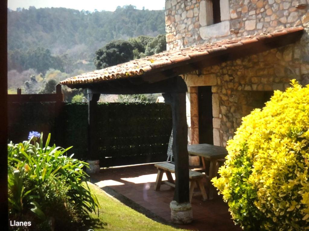 una casa de piedra con un banco en el patio en Casa Lula 2 Pendueles Llanes, en Llanes