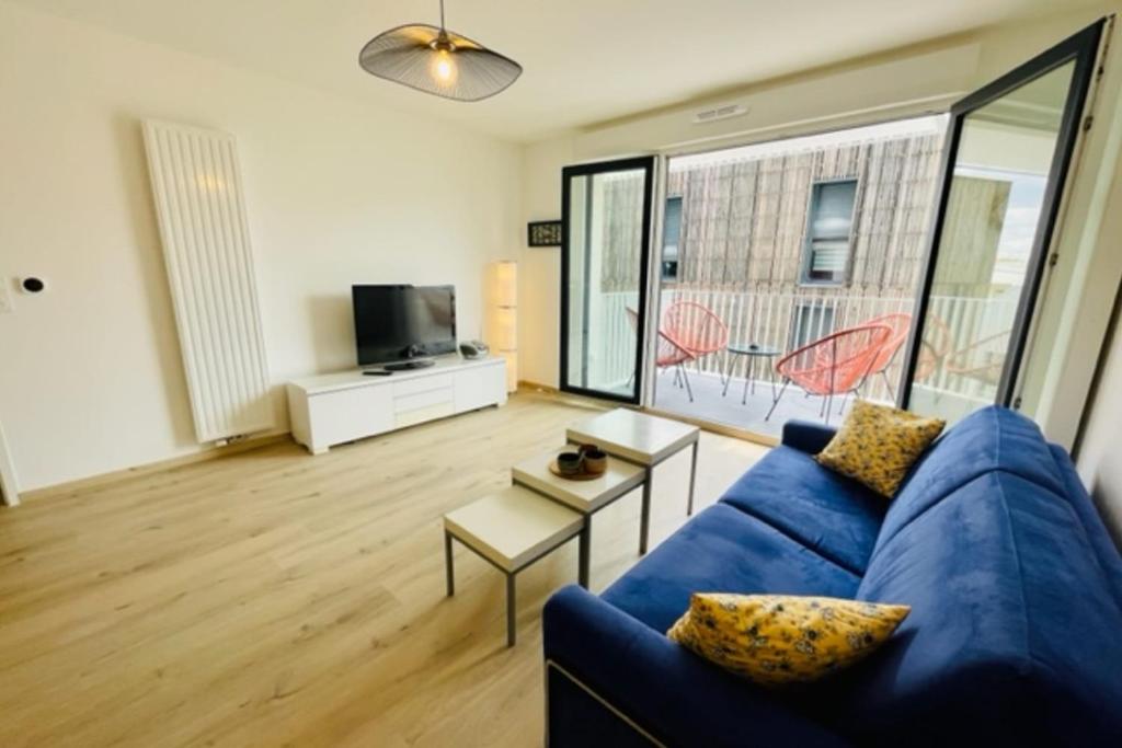 un salon avec un canapé bleu et une télévision dans l'établissement charming new flat with balcony, à La Rochelle