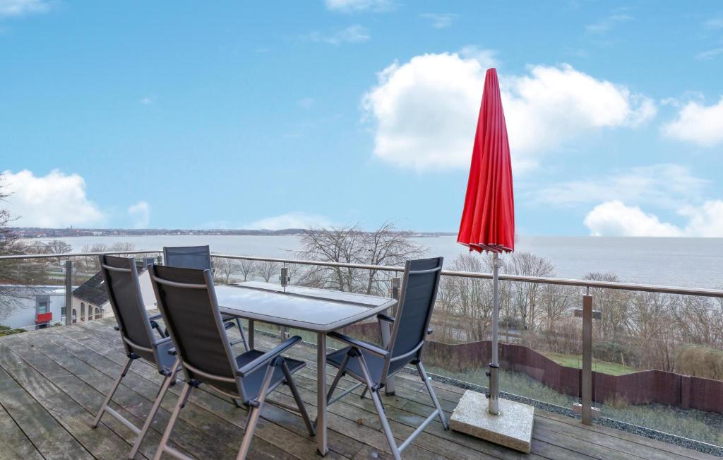 una mesa con sillas y una sombrilla roja en una terraza en Cozy Apartment In Eckernförde, en Eckernförde