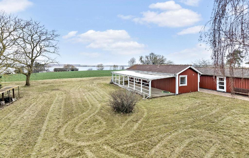 a red barn in a field with a large yard at Beautiful Home In Skibby With House Sea View in Skibby