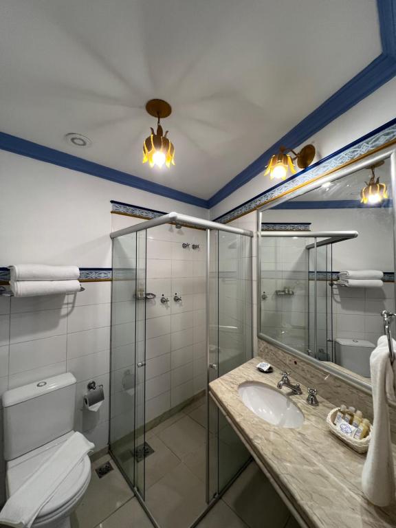 uma casa de banho com uma cabina de duche em vidro e um lavatório. em Pousada Sinhá Olímpia em Ouro Preto