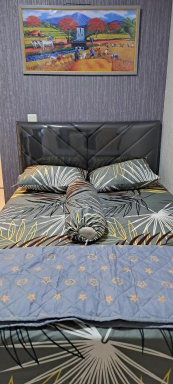 a bed with a blue comforter and pillows at Tower Basella no 2025 - Apartemen Springlake Summarecon Bekasi in Rawabugel