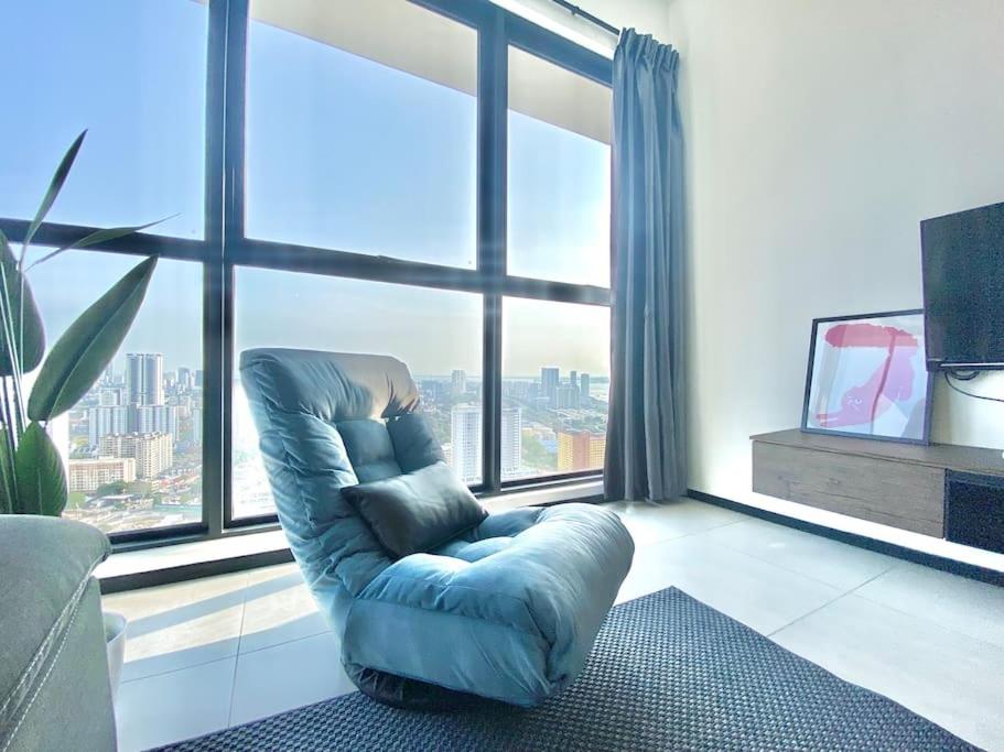 a blue chair in a room with a large window at Urban Suites #High floor view #Infinity Pool #Georgetown #4pax #2BR 2bath #2 Queen #Quality well maintained #Private host in Jelutong