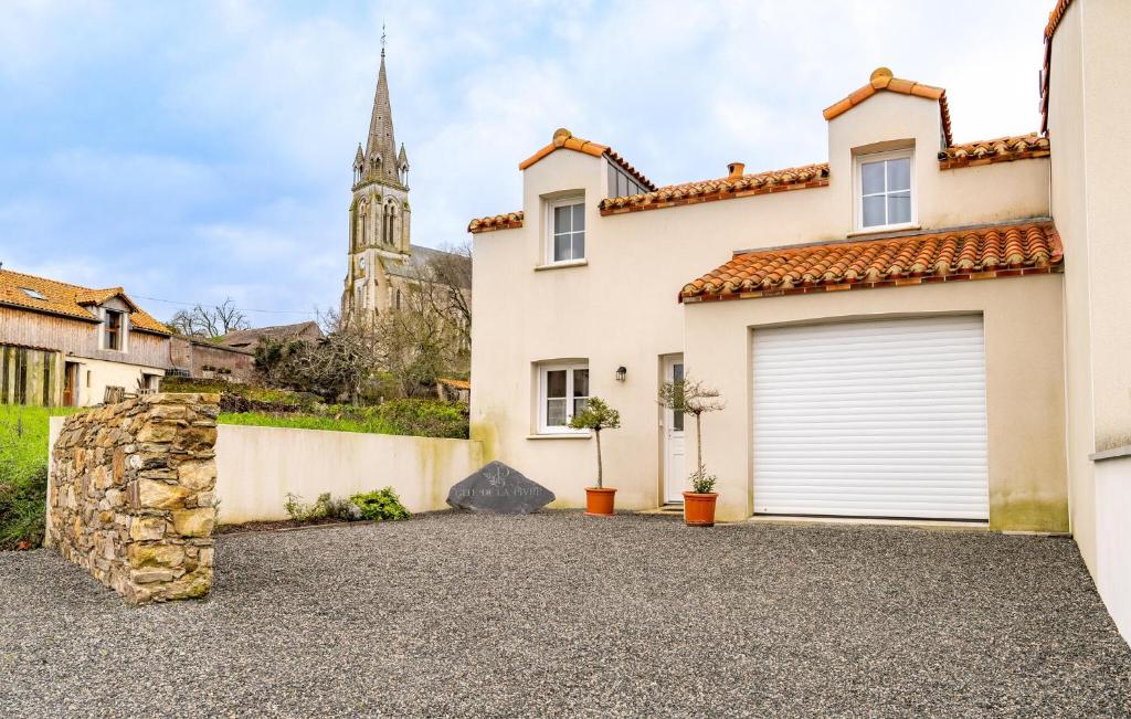 uma casa com uma garagem com uma igreja ao fundo em Nice Home In Saint-viaud With Kitchen em Saint-Viaud