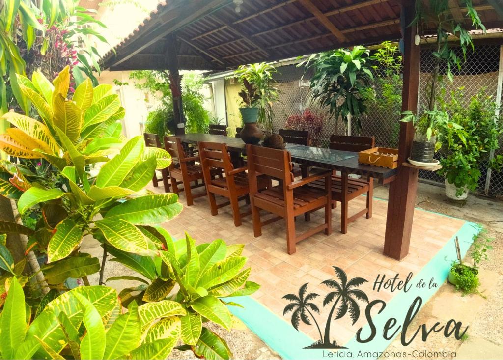 a patio with a table and chairs under an umbrella at Hotel de la Selva in Leticia