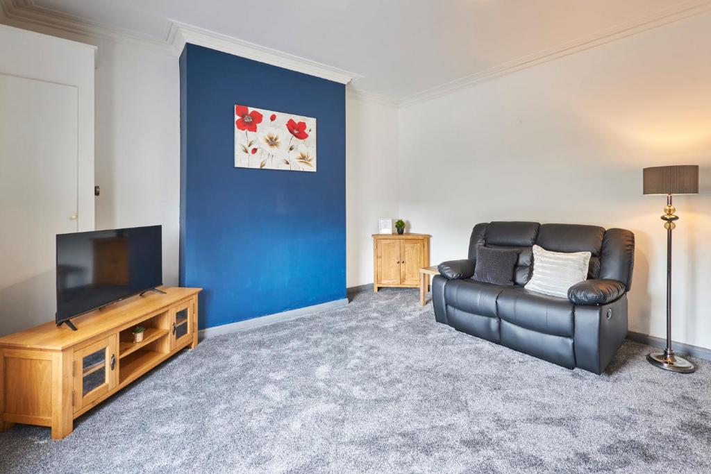 a living room with a black leather couch and a television at Host & Stay - Clarendon Apartments in Redcar