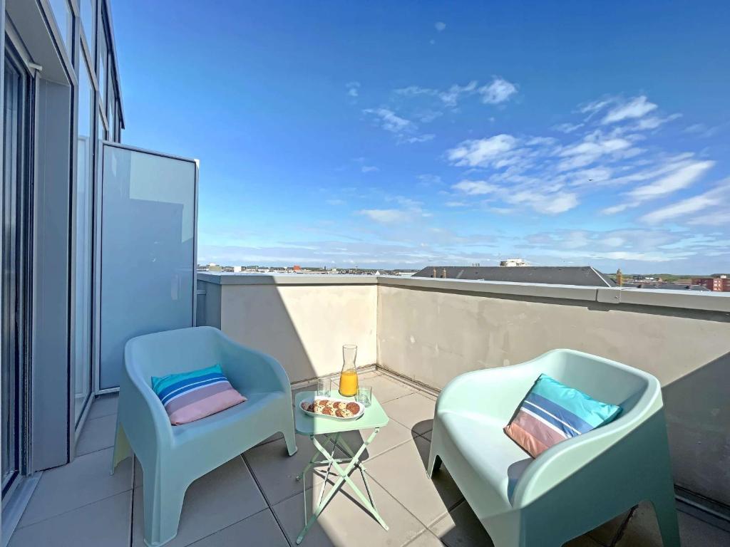 d'un balcon avec deux chaises et une table sur le toit. dans l'établissement Charmant studio pieds dans l'eau - Terrasse & Parking - Résidence récente - FR-1-646-33, à Berck-sur-Mer