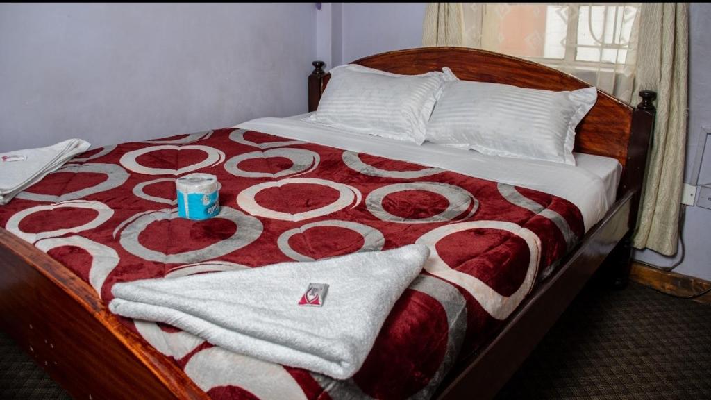 a bed with a red and white blanket with a cup on it at ARRAHMAN HOTEL AND RESTAURANT in Nairobi