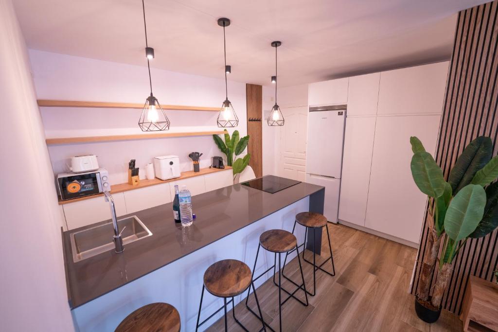 a kitchen with a counter and stools in a room at Apartasuites Royal Zahara, Máximo confort con vistas al mar in Zahara de los Atunes