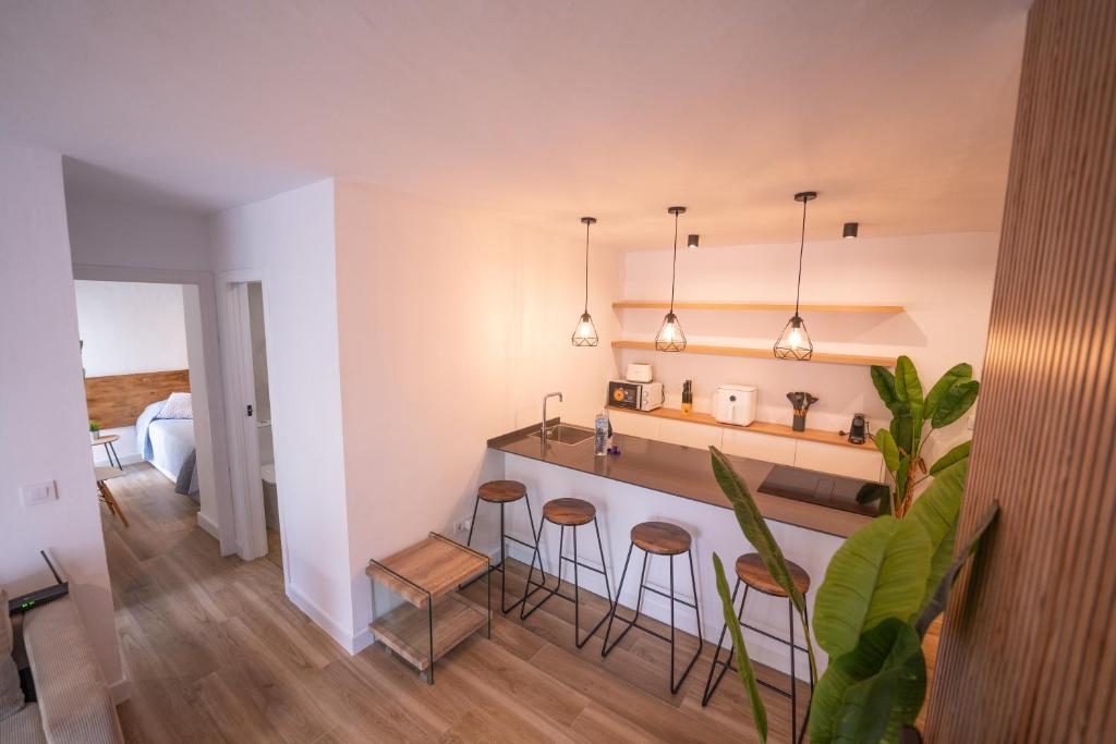 a kitchen with a counter and stools in a room at Apartasuites Royal Zahara, Máximo confort con vistas al mar in Zahara de los Atunes