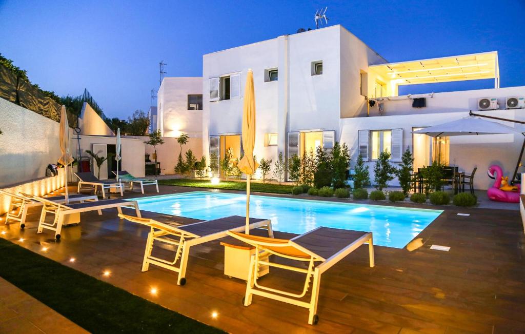 eine Villa mit einem Swimmingpool vor einem Haus in der Unterkunft Cozy Home In Marina Di Ragusa With Wifi in Marina di Ragusa