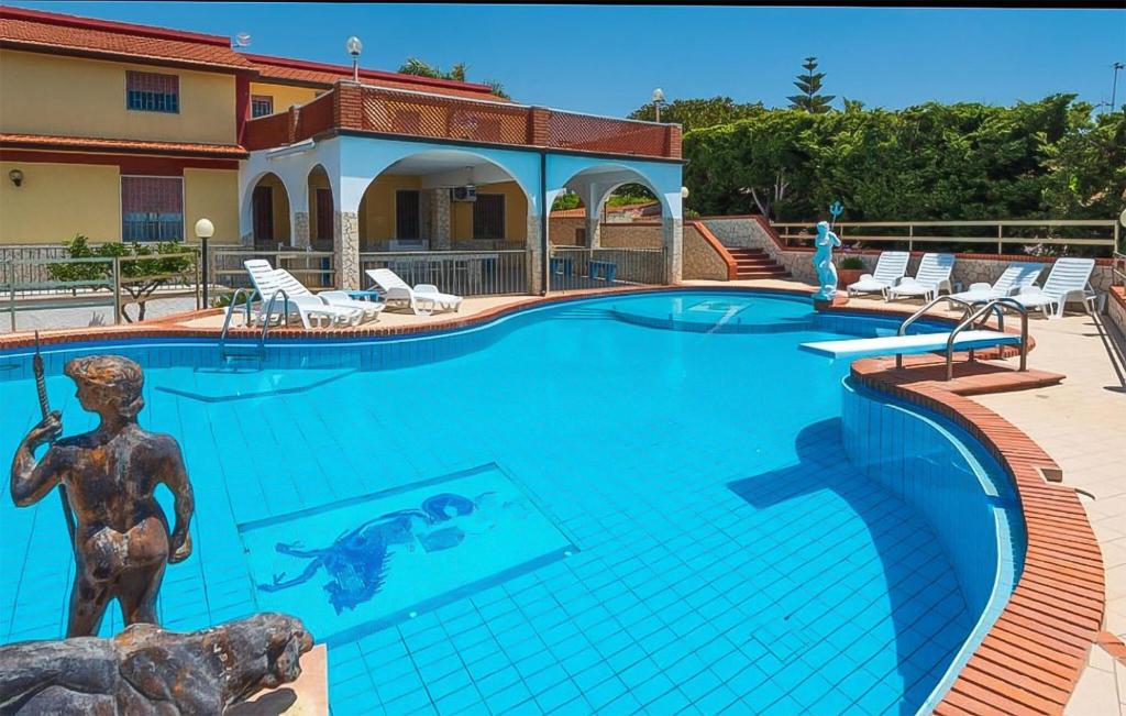 ein Schwimmbad mit einer Statue vor einem Gebäude in der Unterkunft Nice Home In Marina Di Ragusa in Marina di Ragusa