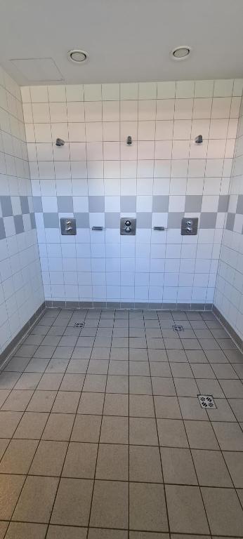 an empty bathroom with blue and white tile walls at INDOOR Camping Sportzentrum Zeltweg in Zeltweg