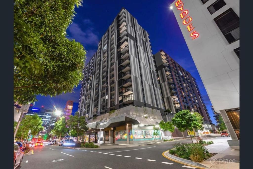 un edificio alto en una calle de la ciudad por la noche en Modern Homely 2BR APT w Parking Bowen Hills en Brisbane