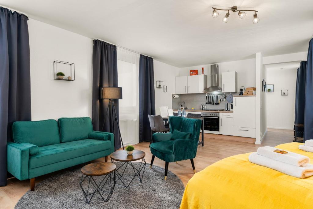a living room with two green chairs and a kitchen at FREE LIVING - City Design Apartments, Zentrum, Outlet, Balkon, Küche in Wolfsburg