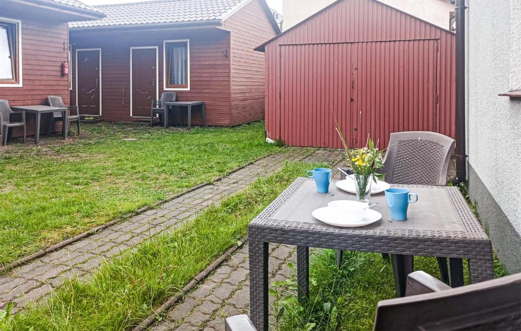 a table with plates and flowers on it in a backyard at Gorgeous Home In Miedzyzdroje With Wifi in Międzyzdroje
