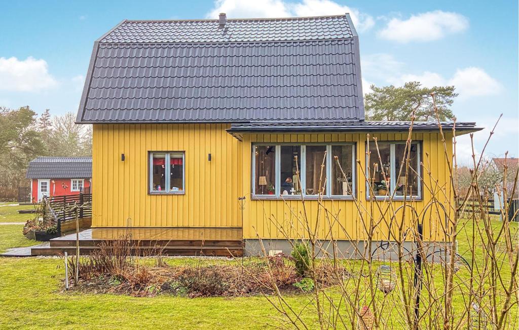 uma casa amarela com um telhado preto num campo em Lovely Home In Lrbro With Kitchen em Lärbro