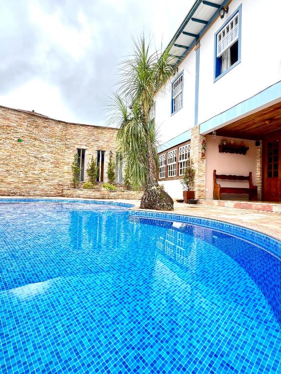 a blue swimming pool in front of a house at Pousada Sinhá Olímpia in Ouro Preto