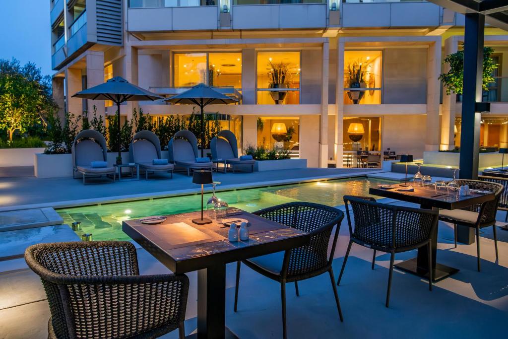 a restaurant with tables and chairs next to a swimming pool at Divani Escape in Athens