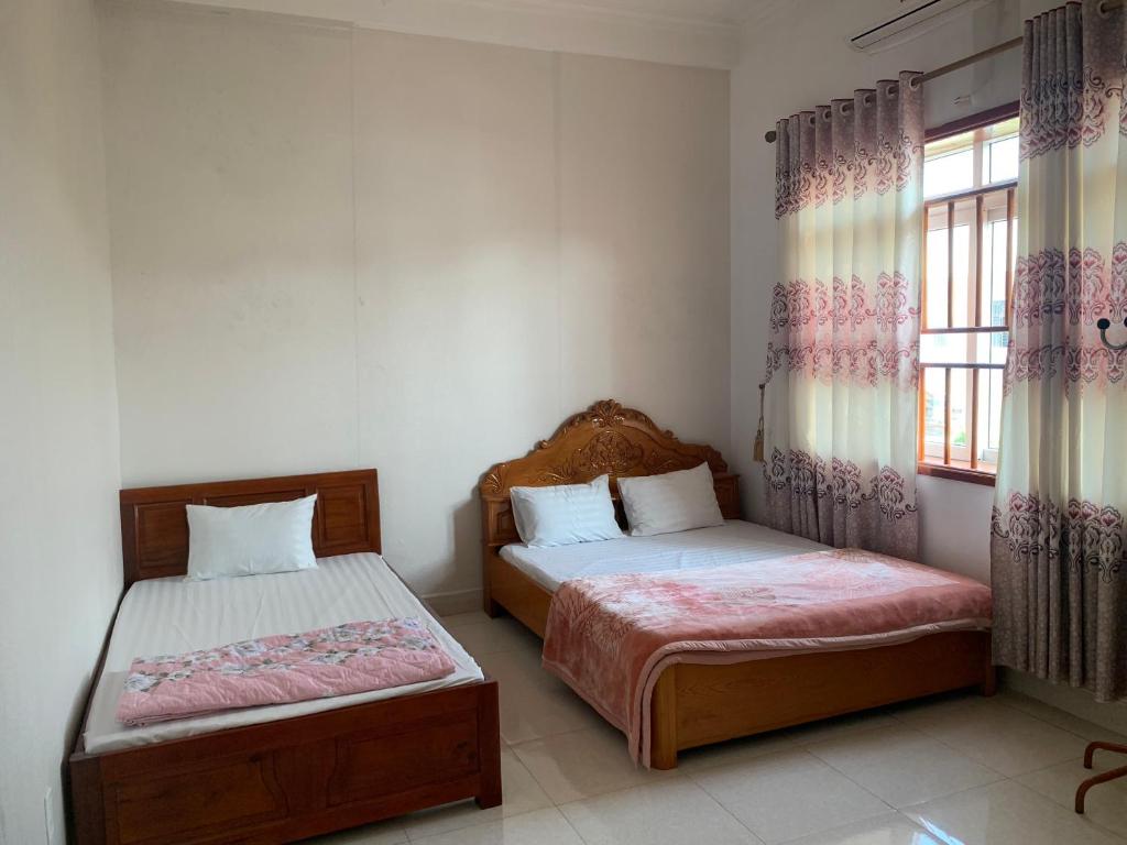 1 dormitorio con 2 camas y ventana en Nhà Nghỉ Hải Nam, en Dien Bien Phu
