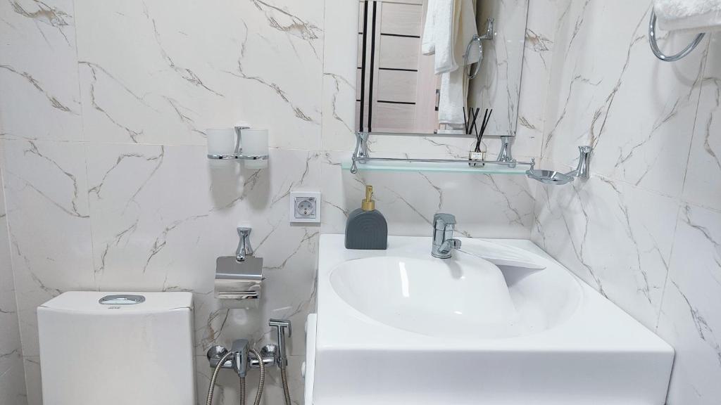 a white bathroom with a sink and a toilet at Mountain View One in Tashkent