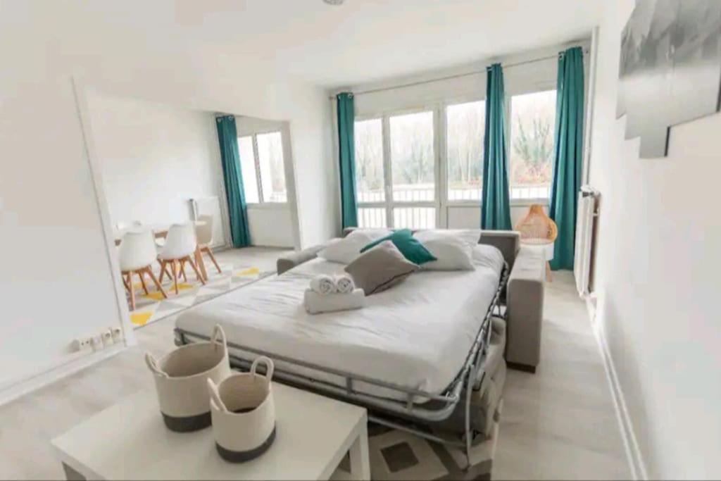 une chambre avec un grand lit avec des rideaux bleus dans l'établissement * Cosy & Spacieux * (75 M2) RER D à 5 min à pied, à Corbeil-Essonnes